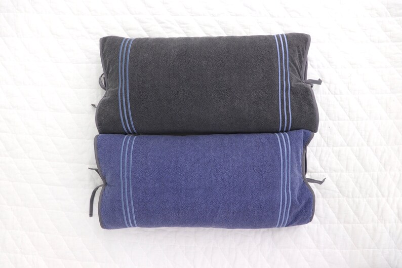 May include: Two decorative pillows, one dark gray and one blue, with light blue trim. The pillows are made of a soft, textured fabric.