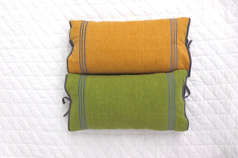 May include: Two decorative throw pillows, one mustard yellow and one green, with dark gray trim and blue stripes.