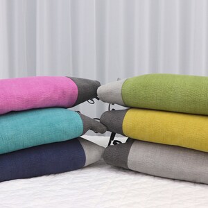 May include: Stack of four colorful cushions with gray trim. The cushions are pink, teal, navy blue, and gray.