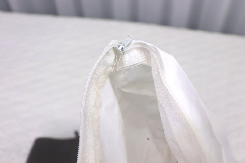 May include: A white zippered pouch with a white zipper pull. The pouch is open and the inside is visible.