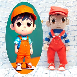 Puede incluir: Dos muñecos de un niño pequeño con un mono naranja y una gorra naranja a juego. Uno es una ilustración de dibujos animados y el otro es un muñeco de tela hecho a mano. El niño de la ilustración lleva una camisa de rayas azules y blancas y zapatillas blancas.
