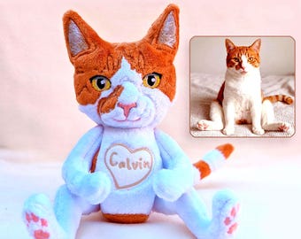 May include: A plush cat toy featuring orange and white fur, yellow eyes, and a heart-shaped patch on its chest with the name Calvin embroidered in brown thread. The toy has pink paw pads and a striped tail, displayed alongside a photo of a real cat.