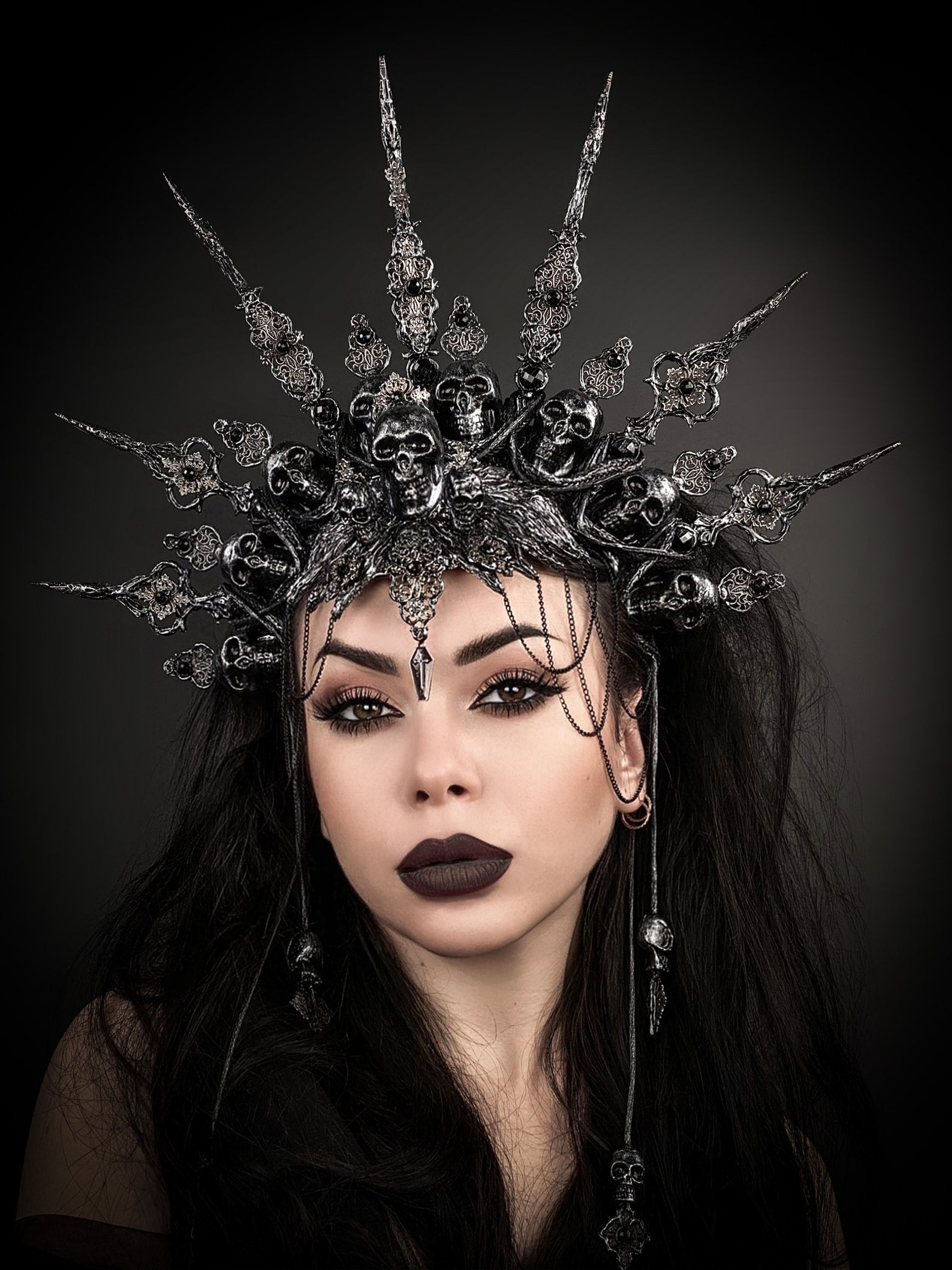 Close-up of pewter skull gothic crown with skull motifs, rhinestones, and spiked halo silhouette on black background