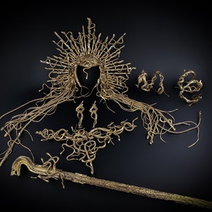 May include: A gold-colored snake-themed jewelry set, including a crown, necklace, earrings, and a staff. The jewelry is made of intertwined snake shapes.