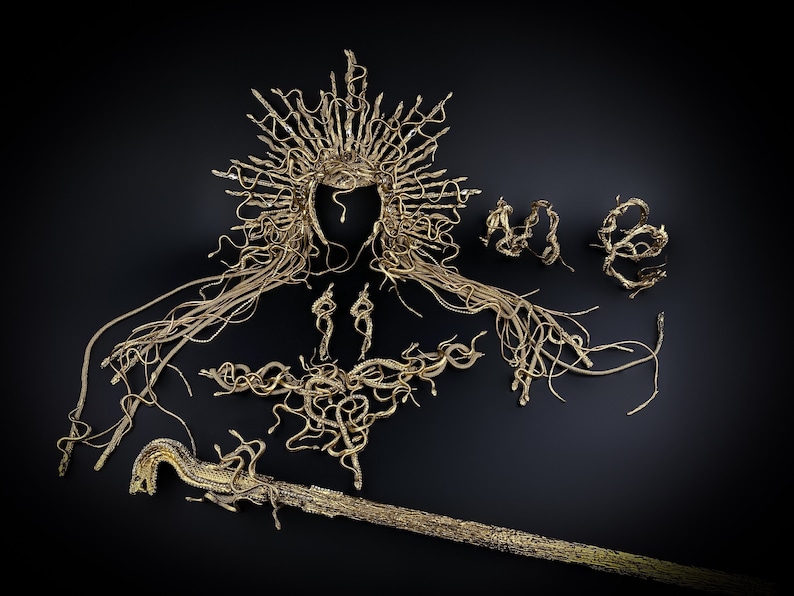 May include: A gold-colored snake-themed jewelry set, including a crown, necklace, earrings, and a staff. The jewelry is made of intertwined snake shapes.