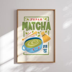 May include: A framed print with a cartoon illustration of a cup of green matcha tea, a whisk, and wooden spoons. The text "JAPAN MATCHA" is in green and pink letters. The text "抹茶" is in blue and red letters.