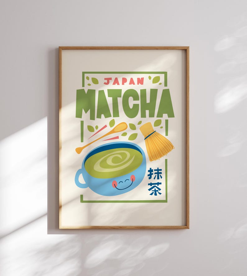 May include: A framed print with a cartoon illustration of a cup of green matcha tea, a whisk, and wooden spoons. The text "JAPAN MATCHA" is in green and pink letters. The text "抹茶" is in blue and red letters.