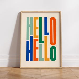 May include: A framed print featuring the word "HELLO" in stacked, colourful letters. The letters are in shades of green, blue, orange, and yellow.