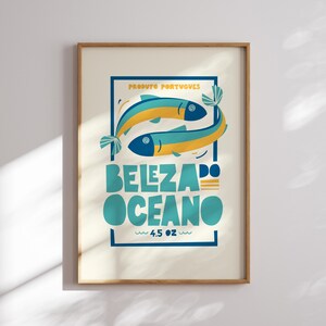 Almanac Co Prints white poster featuring two colorful fish with the text 'Beleza do Oceano' in bold lettering, Portuguese style. Framed in modern kitchen.