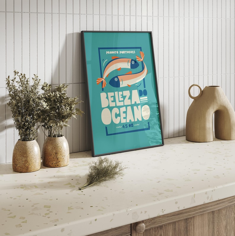 Almanac Co Prints blue poster featuring two colorful fish with the text 'Beleza do Oceano' in bold lettering, Portuguese style. Framed in modern kitchen.