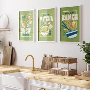 May include: Three framed illustrations of Japanese food and drink. The illustrations are on a green background with white text and images. The first illustration is of sushi with the text "Sushi" and "Kamazama". The second illustration is of matcha with the text "Japan Matcha". The third illustration is of ramen with the text "Umai Ramen" and "Ramen".