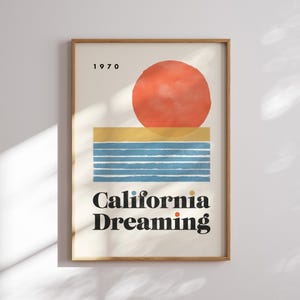 Almanac Co Prints framed poster titled 'California Dreaming' with a red sun, blue waves, and minimalist 1970s design, perfect for home decor. Framed on a white wall.