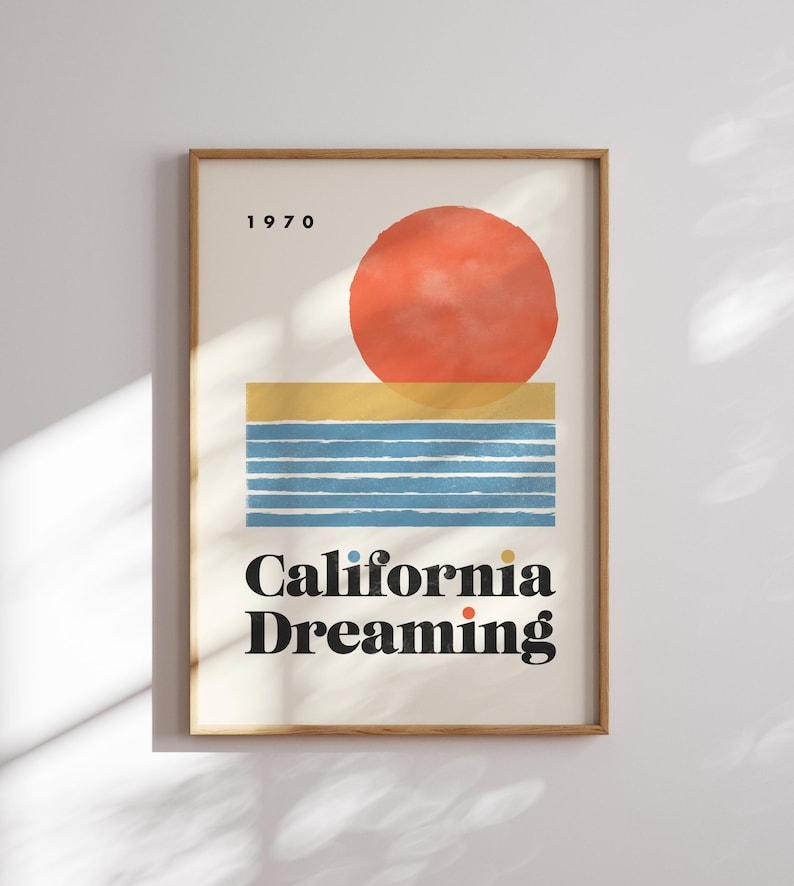 Almanac Co Prints framed poster titled 'California Dreaming' with a red sun, blue waves, and minimalist 1970s design, perfect for home decor. Framed on a white wall.
