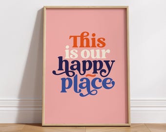 May include: A pink framed print with the text "This is our happy place" in a retro font style. The text is in blue, orange, and white.