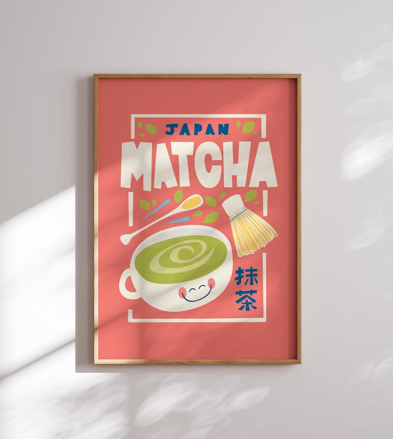 May include: A pink poster with a white frame featuring a cartoon illustration of a bowl of green matcha tea with a whisk and a spoon. The text "JAPAN MATCHA" is in a white box with a blue border. The text "抹茶" is in a red box with a white border.