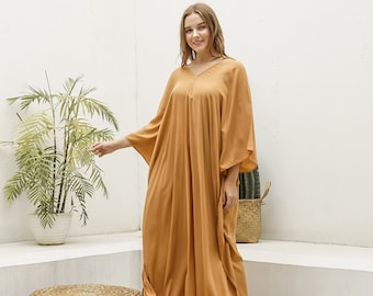 Puede incluir: Un vestido largo de maxi amarillo mostaza holgado con cuello en V y mangas 3/4. El vestido está hecho de una tela suave y fluida y tiene un ajuste relajado.
