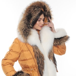 May include: A long, mustard yellow puffer jacket with a large fur hood. The hood is trimmed with white and brown fur. The jacket has a drawstring waist and fur cuffs.