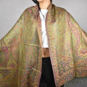 May include: A large, colorful paisley shawl in shades of green, pink, and orange. The shawl features an intricate design with a fringed edge. The fabric appears to be soft and flowing, suitable for draping.