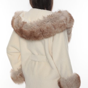 May include: A white fur coat with a brown fur trim around the hood and cuffs.