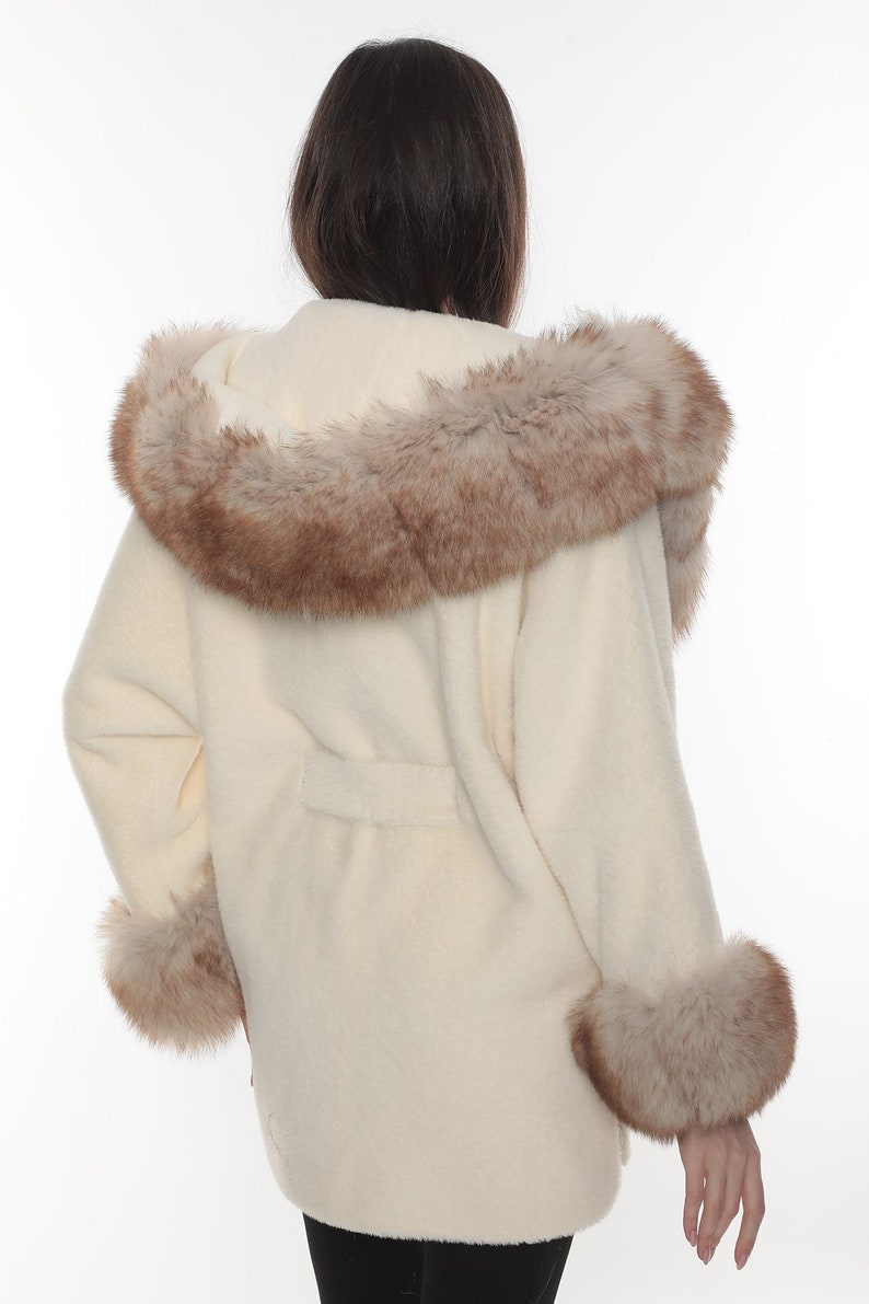 May include: A white fur coat with a brown fur trim around the hood and cuffs.