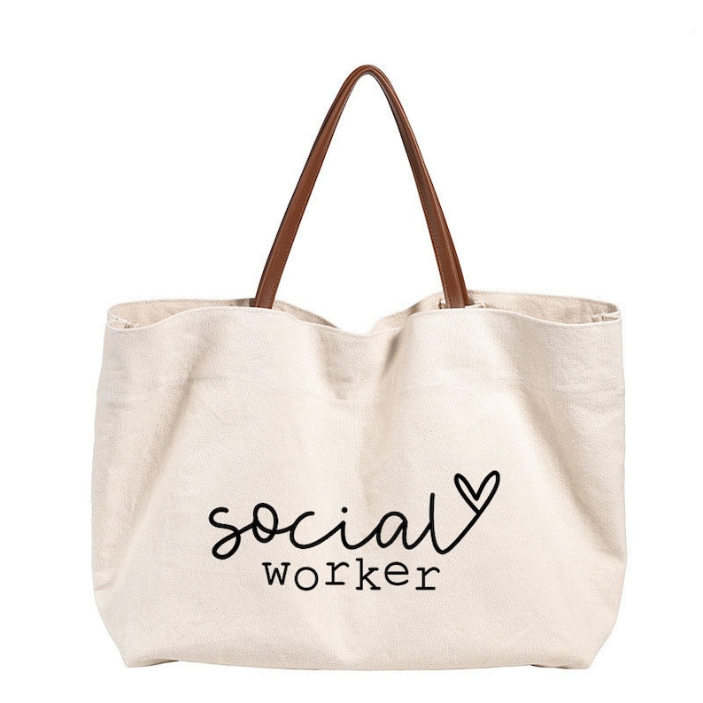 May include: A beige canvas tote bag with brown leather handles. The bag has the text "social worker" with a heart printed on it.