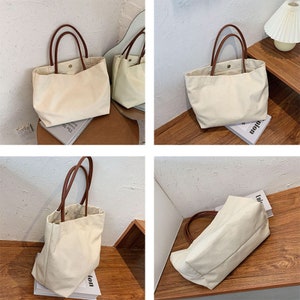 May include: Four images of a beige canvas tote bag with brown leather handles. The bag is shown on a variety of surfaces, including a wooden table, a white surface, and a book.
