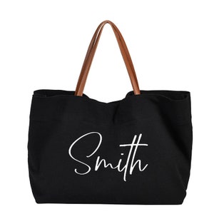 May include: Black canvas tote bag with brown leather handles and the word "Smith" written in white cursive on the front.