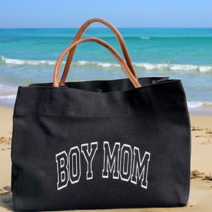 May include: Black canvas tote bag with brown leather handles. The bag has the text "BOY MOM" printed in white on the front.
