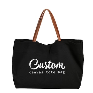 May include: Black canvas tote bag with brown leather handles. The bag has the text "Custom canvas tote bag" printed in white on the front.