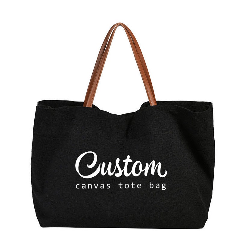 May include: Black canvas tote bag with brown leather handles. The bag has the text "Custom canvas tote bag" printed in white on the front.