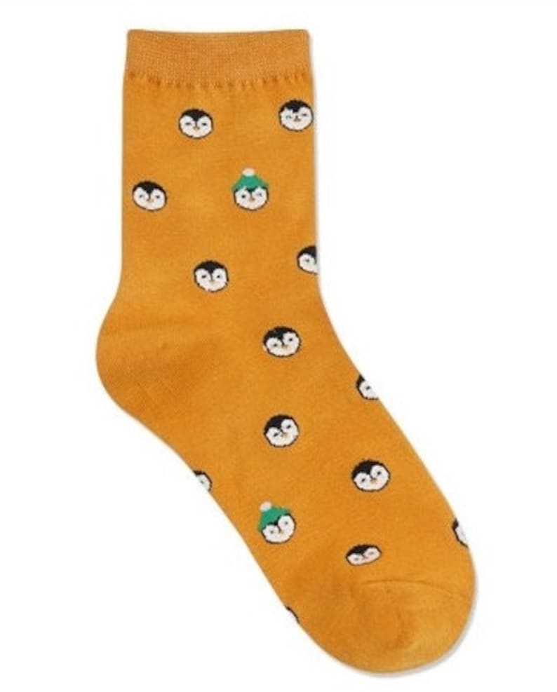 May include: A pair of yellow socks with a pattern of penguins wearing hats. Some penguins are wearing green hats.
