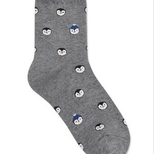 May include: Gray socks with a pattern of penguins wearing hats. Some penguins are wearing blue hats, while others are not.