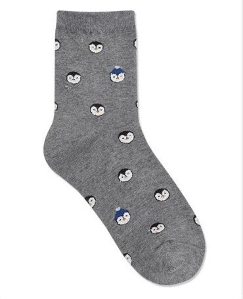 May include: Gray socks with a pattern of penguins wearing hats. Some penguins are wearing blue hats, while others are not.