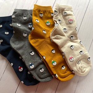 May include: Four pairs of ankle socks with a penguin pattern. The socks are in navy blue, gray, mustard yellow, and beige.