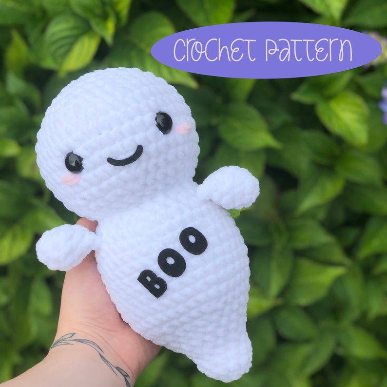 May include: White crocheted ghost amigurumi with black eyes, a smiling mouth, and the word "BOO" written on the front. Crochet pattern.