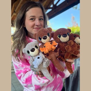 May include: A collection of handmade crochet teddy bears in various colors, including brown, gray, and orange. Each bear has large, expressive eyes and is holding a small crocheted item. The bears are soft and plush, perfect for children.