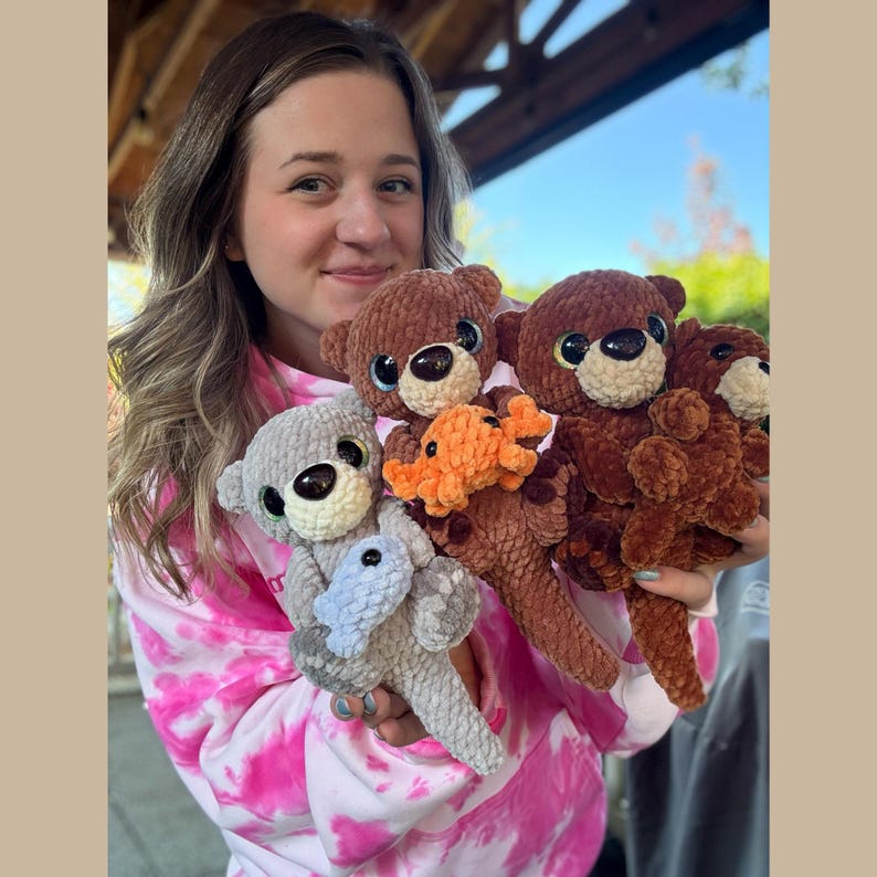 May include: A collection of handmade crochet teddy bears in various colors, including brown, gray, and orange. Each bear has large, expressive eyes and is holding a small crocheted item. The bears are soft and plush, perfect for children.