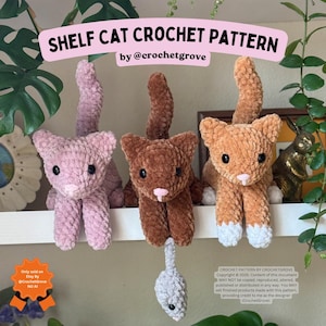 May include: Three plush cat toys made of soft yarn, featuring a pink, a dark brown, and an orange cat with white paws. The cats have black plastic eyes and pink noses. A small gray mouse toy hangs from the brown cat. Text reads SHELF CAT CROCHET PATTERN.