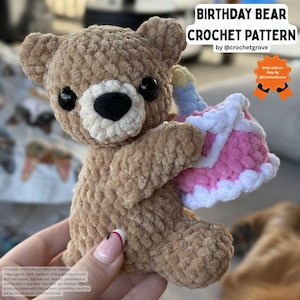 Peut inclure: Un ours en peluche marron crocheté tenant un gâteau d'anniversaire rose et blanc avec une bougie bleue. L'ours a des yeux noirs et un nez noir. Le texte "BIRTHDAY BEAR CROCHET PATTERN" est en haut de l'image.