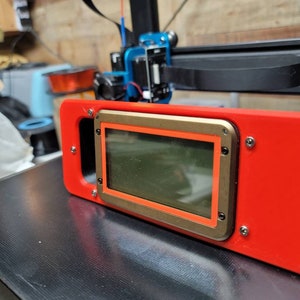 May include: A red 3D printed case with a gold trim and a clear screen. The case has four screws on the side.