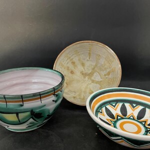 May include: Three ceramic bowls of different sizes and designs. One bowl features a green and white pattern, another is beige with a textured surface, and the third has a geometric pattern with orange and black accents.