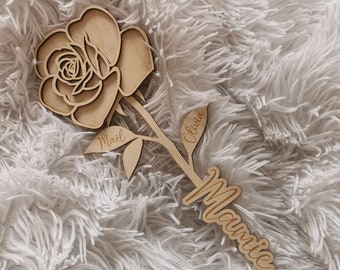May include: Wooden rose with the names "Mael", "Olivia", and "Mamie" engraved on the stem and leaves.