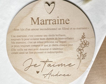 以下が含まれることがあります： ハートと「Marraine」と「Sont liés d'un amour inconditionnel un filleul et sa marraine.」のテキストが書かれた丸い木製のプレート。プレートには花柄のデザインと「Je t'aime Andrea」のテキストも書かれています。