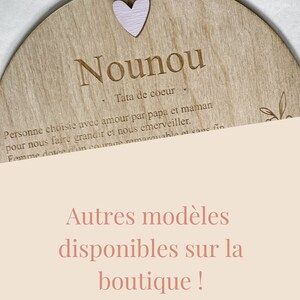 Pu&ograve; includere: Un cartello rotondo in legno con il testo "Nounou Tata de coeur" e un cuore rosa. Il testo continua con "Personne choisie avec amour par papa et maman pour nous faire grandir et nous &eacute;merveiller. Femme dot&eacute;e d'un courage remarquable et sans fin". Il cartello ha anche il testo "Autres mod&egrave;les disponibles sur la boutique!"