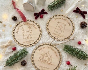 May include: Three round wooden ornaments with scalloped edges. One features a deer and reads Joyeux Noël Maitresse Marion, one a bear and Joyeux Noël Maitre de la part de Lucas 2023, and one a cabin and Joyeux Noël Maitresse de la part de Romy 2025.