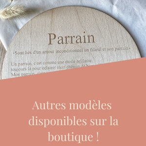 Pu&ograve; includere: Un cartello rotondo in legno con la parola "Parrain" incisa al centro. Il cartello include anche una citazione sull'amore incondizionato tra un padrino e il suo figlioccio. Il testo in basso dice "Autres mod&egrave;les disponibles sur la boutique!"