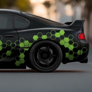 Puede incluir: Un coche negro con un adhesivo de patrón de panal verde en el lateral. El coche tiene un alerón trasero negro y ruedas negras.
