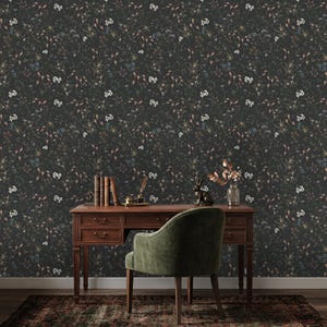 K&ouml;nnte beinhalten: Eine dunkle florale Tapete bedeckt die Wand hinter einem Holzschreibtisch und einem gr&uuml;nen Stuhl. Die Tapete zeigt ein Muster aus kleinen Blumen und Bl&auml;ttern in Wei&szlig;-, Blau- und Braunt&ouml;nen. Eine kleine Hasenstatue und eine Vase mit Blumen stehen auf dem Schreibtisch.