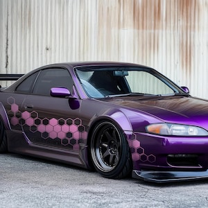 May include: A purple car with a pink and black honeycomb pattern on the side. The car has a black spoiler and black wheels.