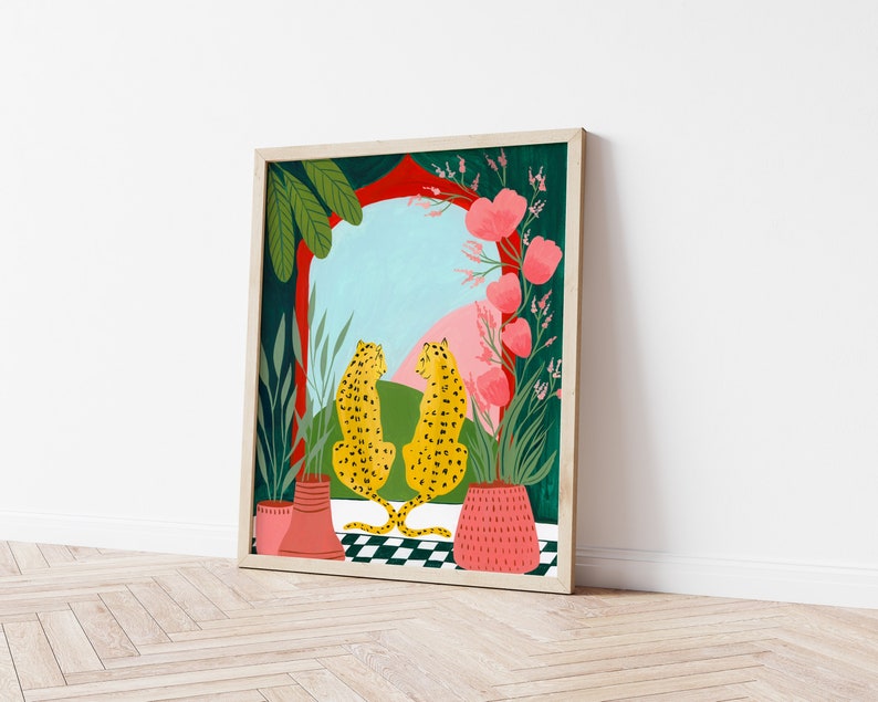 May include: A framed illustration of two yellow leopards with black spots sitting on a checkered floor. The leopards are facing each other and looking out a window with a red archway. The window is framed by green plants and pink flowers.